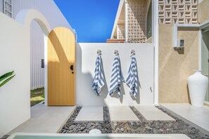 A modern outdoor area with a door, towels, a white vase, and a stone pathway. - Villa Temple of Tides (badung)