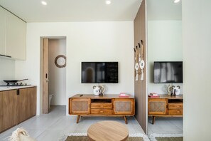A modern living space with a kitchen, a dining area, and a TV mounted on the wall. - Villa Temple of Tides (badung)