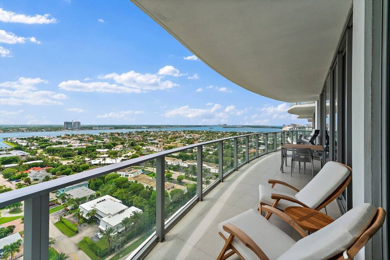 A balcony with a view of a coastal cityscape, furnished with a table and chairs.
