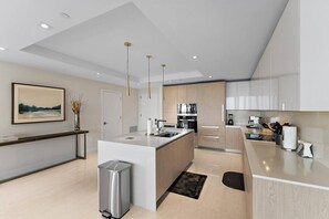 A modern kitchen with a central island, stainless steel appliances, and pendant lighting. - 2BR 2BA in a New Amrit Beach Resort Peace Tower (Riviera Beach)
