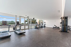A gym with treadmills, stationary bikes, and a weight machine. - 2BR 2BA in a New Amrit Beach Resort Peace Tower (Riviera Beach)