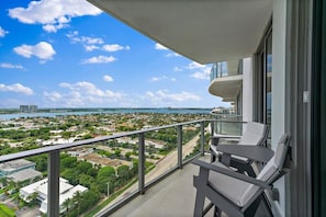 A balcony with a view of a coastal cityscape, including buildings and a body of water. - 2BR 2BA in a New Amrit Beach Resort Peace Tower (Riviera Beach)