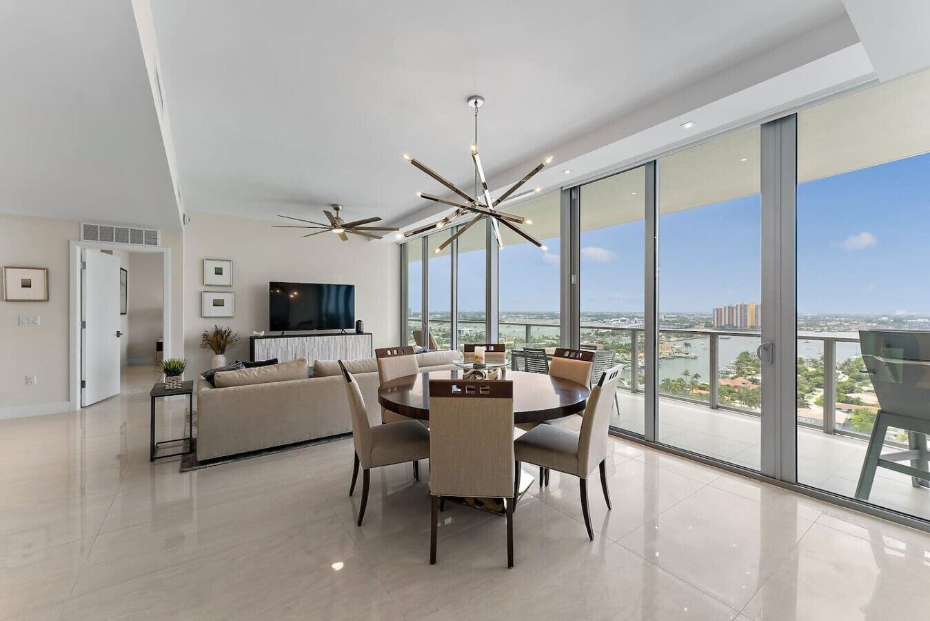 Una sala moderna con comedor, ventanas amplias y vista a la ciudad.