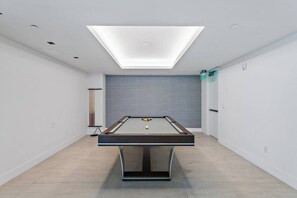 Ein Billardtisch in einem Raum mit Oberlichter, grauer Wand und Holzboden.