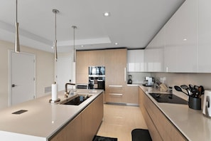 A modern kitchen with a central island, stainless steel appliances, and wooden cabinetry. - 2BR 2BA in a New Amrit Beach Resort Peace Tower (Riviera Beach)