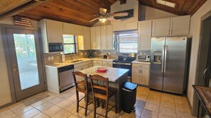 A modern kitchen with a central island, stainless steel appliances, and a ceiling fan. - Welcome to the Bay House! (St George Island)
