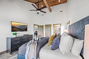 Ein Schlafzimmer mit einem Bett, einem Deckenventilator, einer Kommode und einem Gemälde an der Wand.
