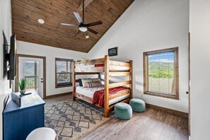 A bunk bed room with a ceiling fan, a desk with a plant, and a window with blinds. - Stunning Mountain Views! 3BR Cabin w/ Hot Tub, Fire Pit & Games (Gatlinburg)