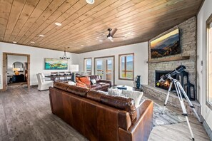 A spacious living room with a leather sofa, a fireplace, and a telescope. - Stunning Mountain Views! 3BR Cabin w/ Hot Tub, Fire Pit & Games (Gatlinburg)