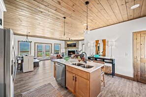 Eine moderne Küche mit Holzboden, einer zentralen Kochinsel und einem Essbereich mit Ausblick.