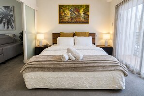 A hotel room with a large bed, two bedside lamps, a painting on the wall, and a view through sheer curtains. - Kivuli | Elegant 1BR • Perth CBD • Parking. (Perth)