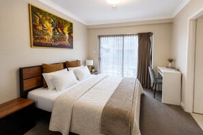 Una habitación de hotel con una cama grande, un escritorio y un cuadro en la pared.