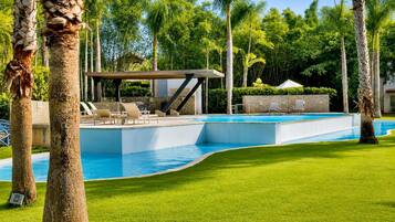 A swimming pool with a lounge area, surrounded by palm trees and a well-maintained lawn.