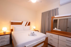 A hotel room with a bed, bedside tables, a mirror, a wardrobe, and a ceiling fan. - NOK Cozy 2BR Stay in Vistacana Punta Cana (Punta Cana)