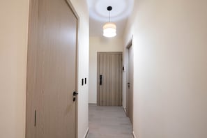 A hallway with wooden doors and a ceiling light fixture. - NOK Cozy 2BR Stay in Vistacana Punta Cana (Punta Cana)