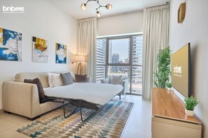 Een moderne hotelkamer met een bed, bank, kunstwerken, een televisie en uitzicht op de stad.