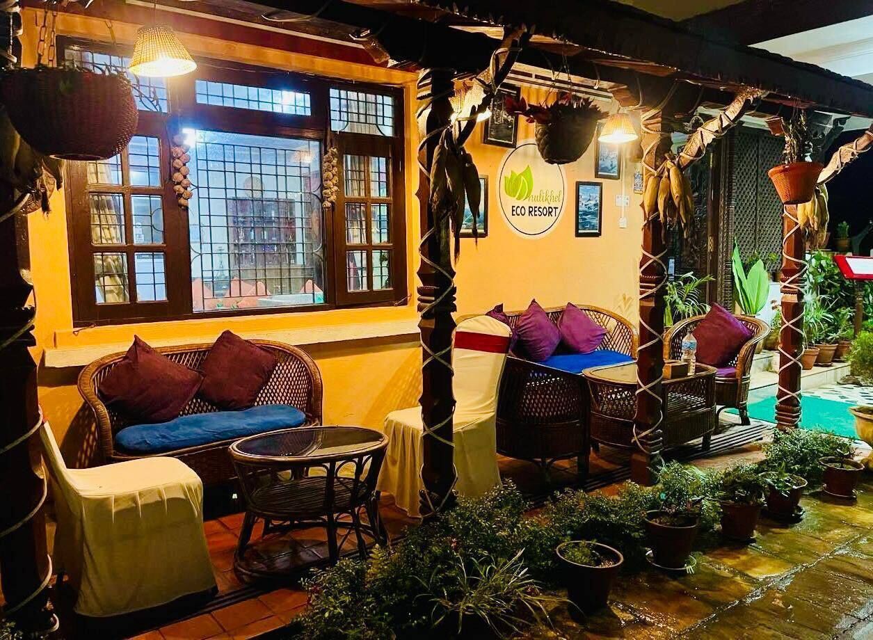 An outdoor seating area with wicker furniture, a round table, and potted plants.