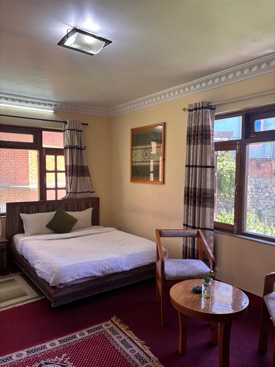 A bedroom with a bed, a chair, a table, and a window with curtains.