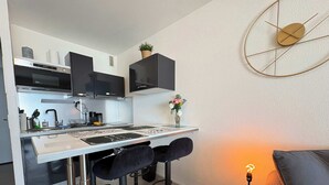 A modern kitchen with a white countertop, black cabinets, and a bar stool seating arrangement. - Cozy Seafront Studio on the Mediterranean (Agde)
