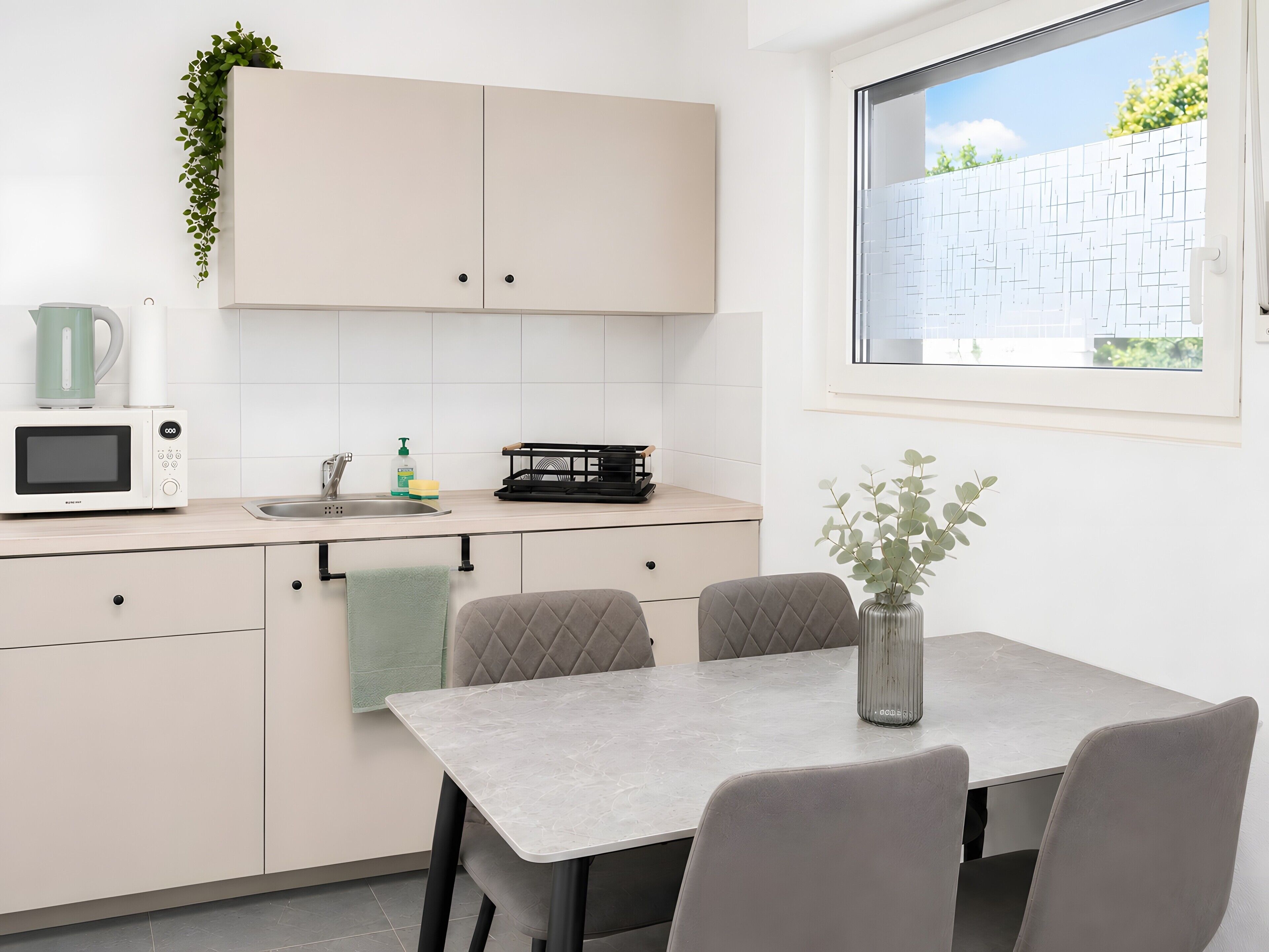 Une cuisine moderne équipée d’un four à micro-ondes, d’un évier et d’un coin repas avec des chaises et une table.