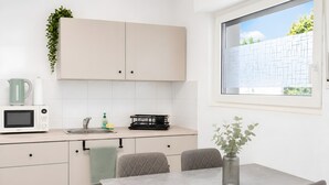 Una cocina moderna con microondas, pileta y comedor con sillas y mesa.