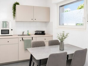 Eine moderne Küche mit Mikrowelle, Spüle und Essbereich mit Stühlen und einem Tisch.