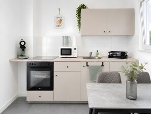 Eine moderne Küche mit Einbauofen, Mikrowelle und Kaffeemaschine. Ein Esstisch mit einer Vase und einem Stuhl steht daneben.