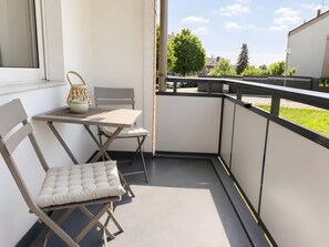 Ein Balkon mit Tisch und Stühlen sowie Blick auf die Nachbarschaft und einem Geländer.