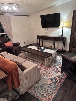 A living room with a sofa, coffee table, and a television mounted on the wall.