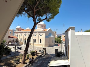 A building with a dome and arched windows, a tree in the foreground, and a clear blue sky. - Elia Central Kos Old town (Kos)