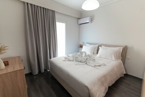 A hotel room with a bed, a bedside table, a lamp, and an air conditioning unit. - Elia Central Kos Old town (Kos)