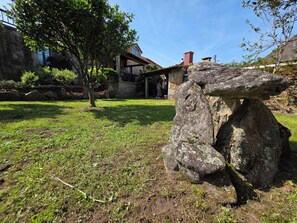 Una escultura de piedra en un césped, con un edificio al fondo.