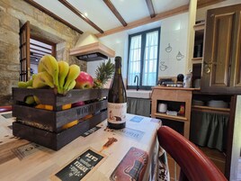Uma cozinha com uma caixa de madeira cheia de frutas, uma garrafa de vinho e uma máquina de café.