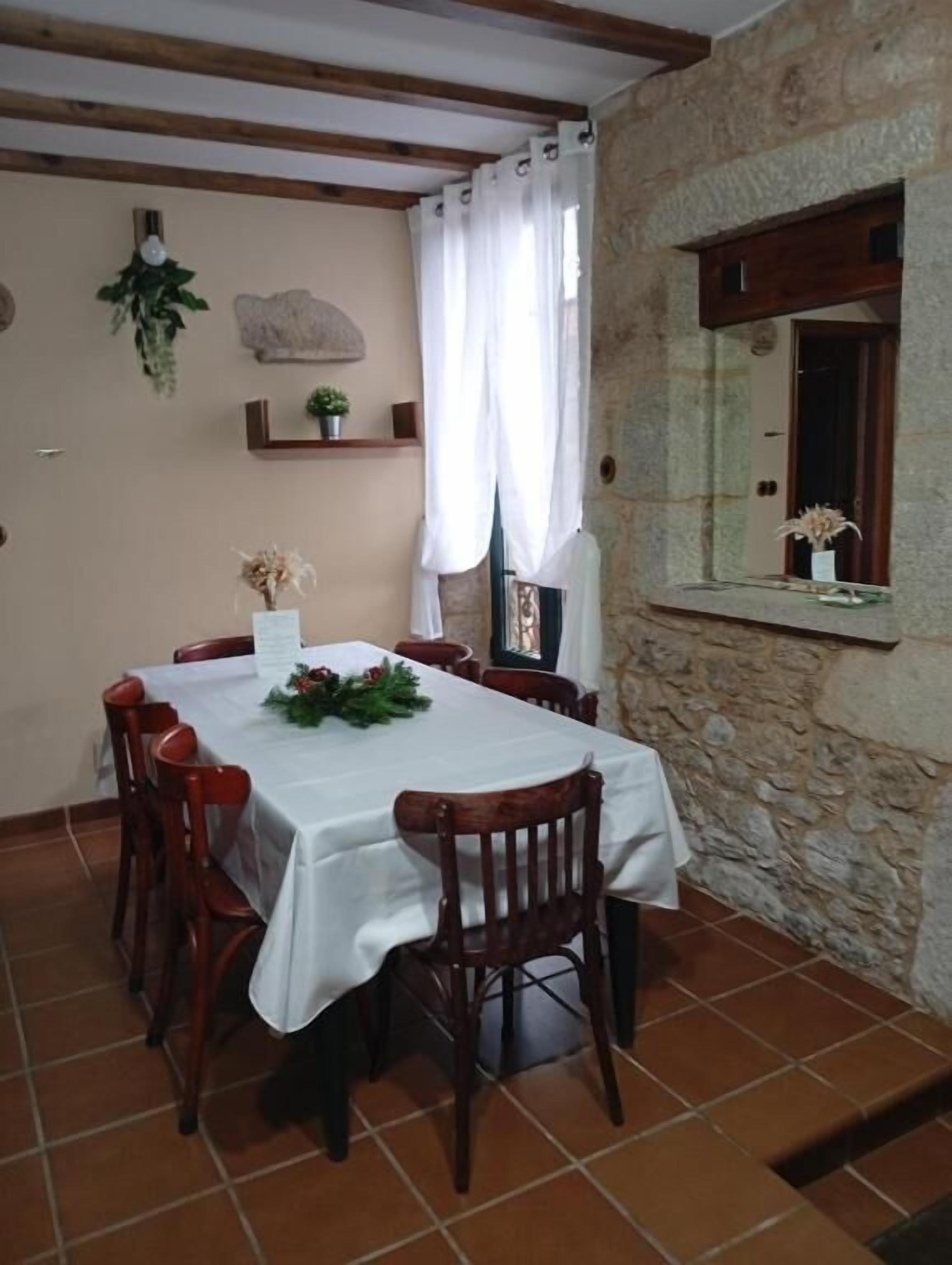 A dining area with a table set for four, surrounded by wooden chairs.