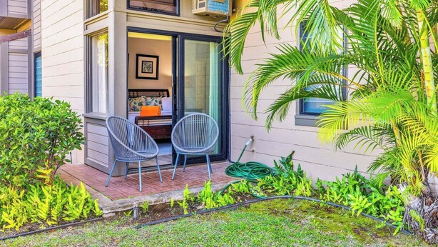 A modern building with a balcony, two chairs, and lush greenery. - Kapalua Ridge | 2 Ocean View Villas, Sleeps 12 | Car Incl. w/ 6+ Nights | ML-4253 by KBM (Lahaina)