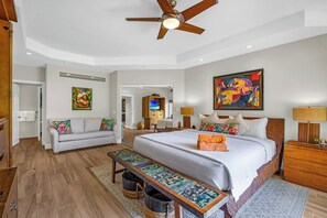 A hotel room with a bed, a sofa, a desk, a ceiling fan, and artwork on the walls. - Kapalua Ridge | 2 Ocean View Villas, Sleeps 12 | Car Incl. w/ 6+ Nights | ML-4253 by KBM (Lahaina)