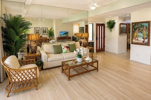 A spacious living room with a sofa, coffee table, and wicker chairs. There are potted plants and artwork on the walls. - Kapalua Ridge | 2 Ocean View Villas, Sleeps 12 | Car Incl. w/ 6+ Nights | ML-4253 by KBM (Lahaina)