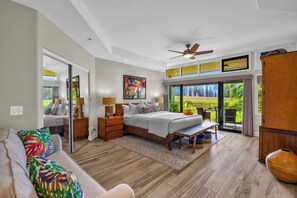 A spacious bedroom with a large bed, a ceiling fan, and a view of a lush garden through a sliding door. - Kapalua Ridge | 2 Ocean View Villas, Sleeps 12 | Car Incl. w/ 6+ Nights | ML-4253 by KBM (Lahaina)