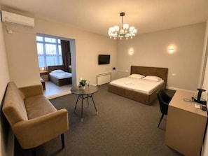 Une chambre d’hôtel comprenant un lit, un bureau, une chaise, une petite table et un canapé.
