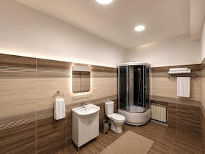 Une salle de bain moderne avec une douche à parois incurvées, un lavabo blanc et des toilettes.