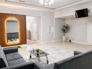 A modern living room with a sofa, coffee table, and a flat-screen TV mounted on the wall. - Grand Sky Hotel (Almaty)