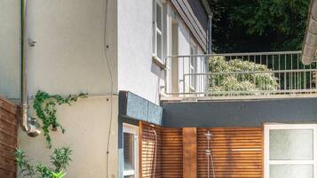 Una piscina exterior con un deck de madera, sillas de descanso y una pequeña zona ajardinada.