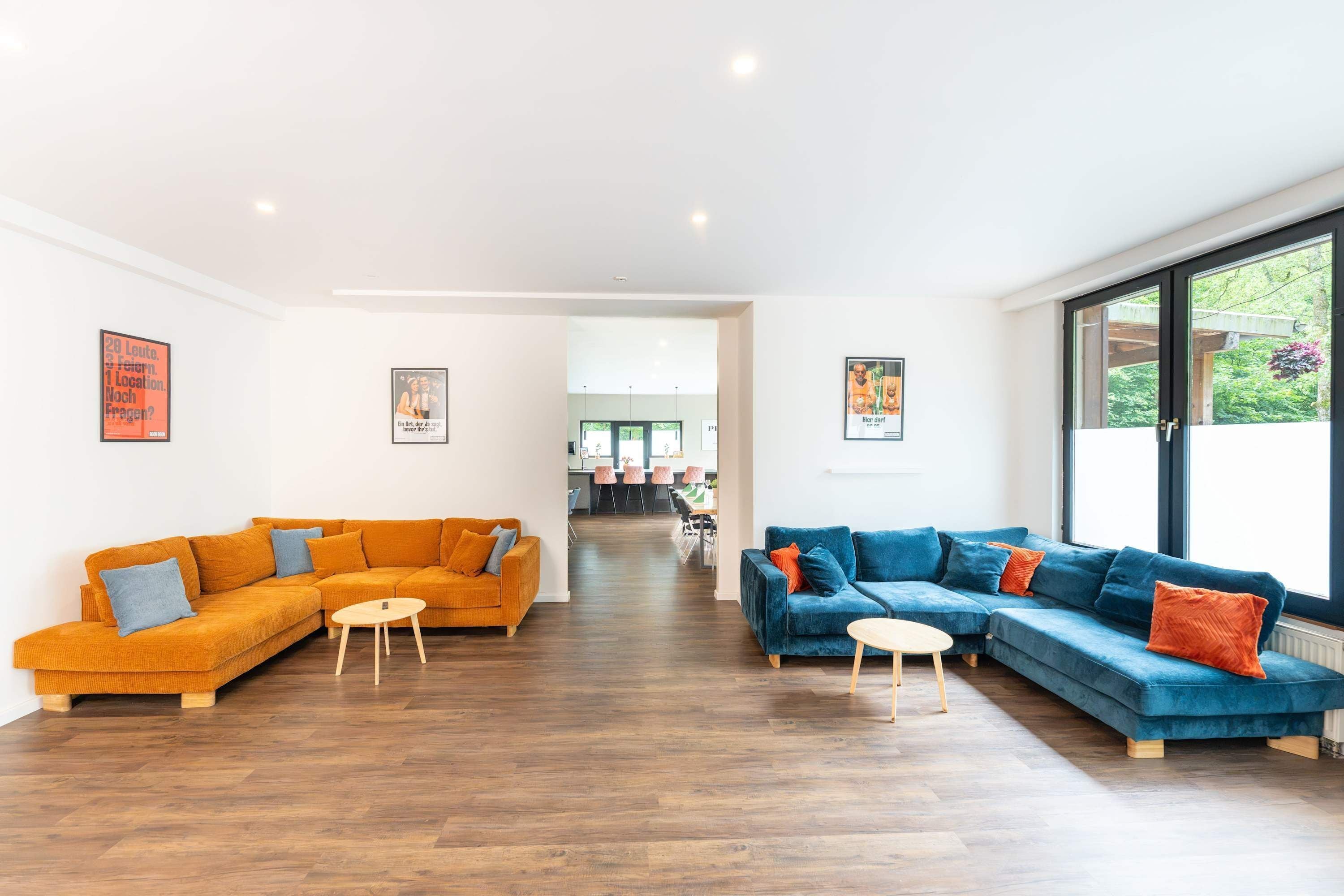 A spacious living area with two sofas, a coffee table, and a dining area in the background.