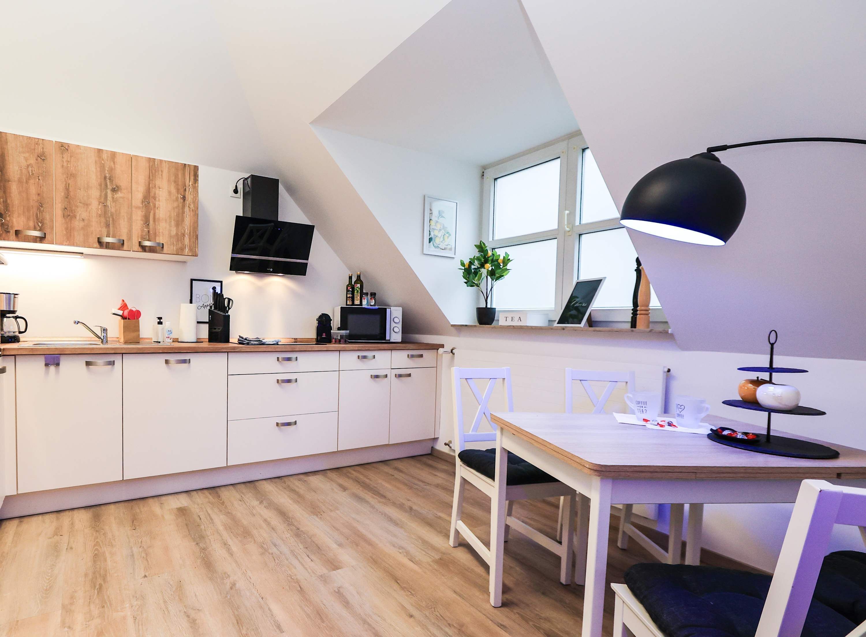 A modern kitchen with white cabinets, a wooden countertop, and a dining area with a table and chairs.