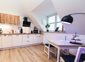 Una cocina moderna con armarios blancos, encimera de madera y zona de comedor con mesa y sillas.