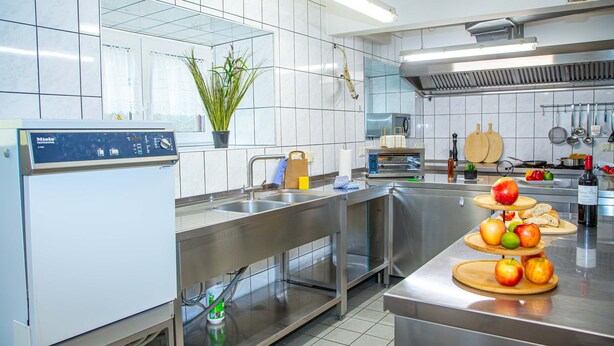 Una cocina moderna con electrodomésticos de acero inoxidable, horno empotrado y una variedad de utensilios de cocina.