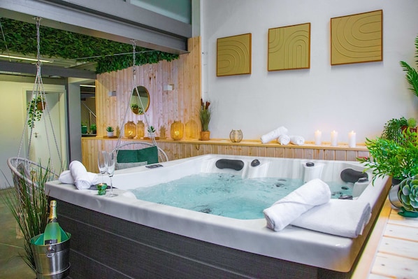 A spa room with a hot tub, wooden panel wall, and wall-mounted artwork.
