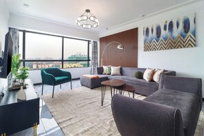 A modern living room with a sofa, armchairs, a coffee table, and a large window offering a city view. - Staroot - The City Elegance  (Nairobi)