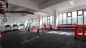Ett gym med löpband, motionscyklar, en roddmaskin och ett ställ med hantlar.