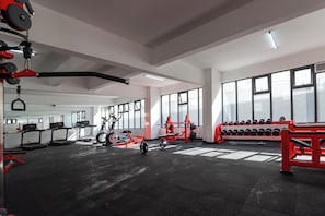 A gym with treadmills, stationary bikes, a rowing machine, and a rack of dumbbells.